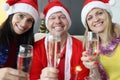 Man and two women in santa claus hats holding glasses of champagne for new year Royalty Free Stock Photo