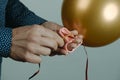 Man tying a golden balloon to a ribbon Royalty Free Stock Photo