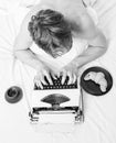 Man with typewriter and coffee lay bed. Author guy tousled hair busy write chapter deadline coming top view. Man