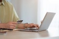 A man typing his credit card number on a shopping website via his laptop while sitting at a table Royalty Free Stock Photo