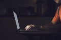 Man typing on keyboard and working at computer laptop in night