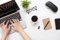 Man typing on laptop computer over white office desk table with cup of coffee and office supplies. Top view, flat lay Royalty Free Stock Photo