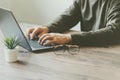 Man typing on a laptop keyboard on a wooden table and tree Royalty Free Stock Photo