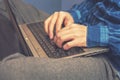 A man is typing on a laptop while sitting on the couch. Vintage tinted glass.