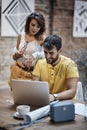 Man typing on laptop, smiling, with beautiful female leaned on his shoulder