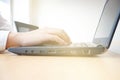 Man typing laptop on wooden table in meeting room sunlight from window