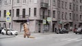 Man in tyrannosaurus costume prankster walking at city street crosswalk