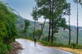 Man with umbrella on curvy Himalayan road,monsoon landscape of Garhwal, Uttarakhand, India. Climate change effect on Himalays