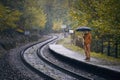 Man with umbrella during rain waiting at railroad station