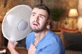 Man during unbearable heatwave using electric fan