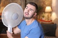 Man during unbearable heatwave using electric fan