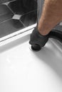 Man unblocking pipes in a bathroom shower cubicle using a hoover.