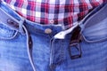 Man unbuckled his belt and unbuttoned jeans by hands after having a heavy dinner.