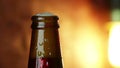 Man uncork a bottle of beer with foam with ice frozen drops, on gold brown background, fun and nutrition