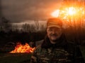 A man in uniform armed with a fire. Smile of the prankster. In the background, the building burns