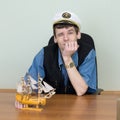 Man in a uniform cap at table with ship Royalty Free Stock Photo