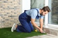 Man in uniform cutting artificial grass carpet Royalty Free Stock Photo