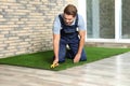 Man in uniform cutting artificial grass carpet Royalty Free Stock Photo