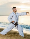 Man in uniform doing taekwondo exercises at sunset sea shore Royalty Free Stock Photo