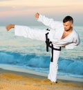 Man in uniform doing taekwondo exercises at sunset sea shore Royalty Free Stock Photo