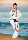 Man in uniform doing taekwondo exercises at sunset sea shore Royalty Free Stock Photo