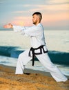 Man in uniform doing taekwondo exercises at sunset sea shore Royalty Free Stock Photo