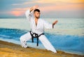 Man in uniform doing taekwondo exercises at sunset sea shore Royalty Free Stock Photo