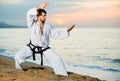 Man in uniform doing taekwondo exercises at sunset sea shore Royalty Free Stock Photo