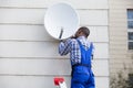 Man In Uniform Fitting TV Satellite Dish Royalty Free Stock Photo