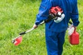 A man in a uniform with a lawn mower is going to cut green grass Royalty Free Stock Photo