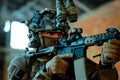 Man in uniform with machine gun and night-vision device, move in broken building. Closeup airsoft soldier aims at the sight in