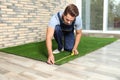 Man in uniform measuring artificial grass carpet Royalty Free Stock Photo