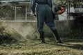 Man in uniform mowing grass with electric mower. The felling of the weed