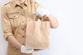 A man in a uniform and white gloves is holding a paper shopping bag. The concept of service delivery. Advertising space. Copy of