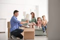 Man unpacking box while his family sitting on sofa indoors. Moving into new house Royalty Free Stock Photo