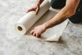 Man unraveling a rolled white wallpaper, illustrating home renovation and interior design in process