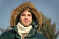 Man unshaven wear warm jacket with fur snowy nature background. Guy wear winter jacket with furry hood. Hipster winter