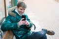 Man unshaven wear warm jacket and hold smartphone snowy urban background. Communication concept. Hipster use smartphone
