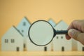 Man use magnifying glass search wooden houses. House searching concept. Home appraisal. Search for housing