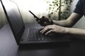 Man use smartphone and laptop in office or at home. Side view shot of male typing keyboard and using mobile phone Royalty Free Stock Photo