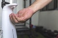 A man uses an automated hand sanitizer prior to entering a small gym