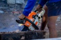 Man uses gasoline engine portable chainsaw cut timber into pieces
