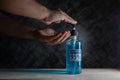 Man uses hand sanitizer blue gel with ingredient ethyl alcohol 95% on wooden table with dark background