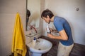 A man uses an oral irrigator in his bathroom