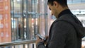 Man uses phone in shopping center. Media. Young man is dependent on phone and social networks even while shopping