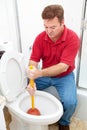 Man Uses Plunger on Clogged Toilet Royalty Free Stock Photo