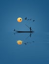 A man uses a pole to move a small boat and he is joined by a flock of pelicans