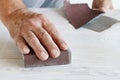 Man uses a sandpaper to restore wooden surface