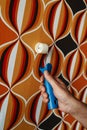 man uses a seam roller on a wallpapered wall