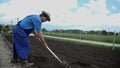 Man uses the shovel to manually turn around some of the soil